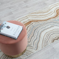 Pink ottoman with a book on a patterned rug