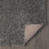 Rectangular grey shaggy rug with dense polyester fibers and a fabric-backed underside shown on wood floor.