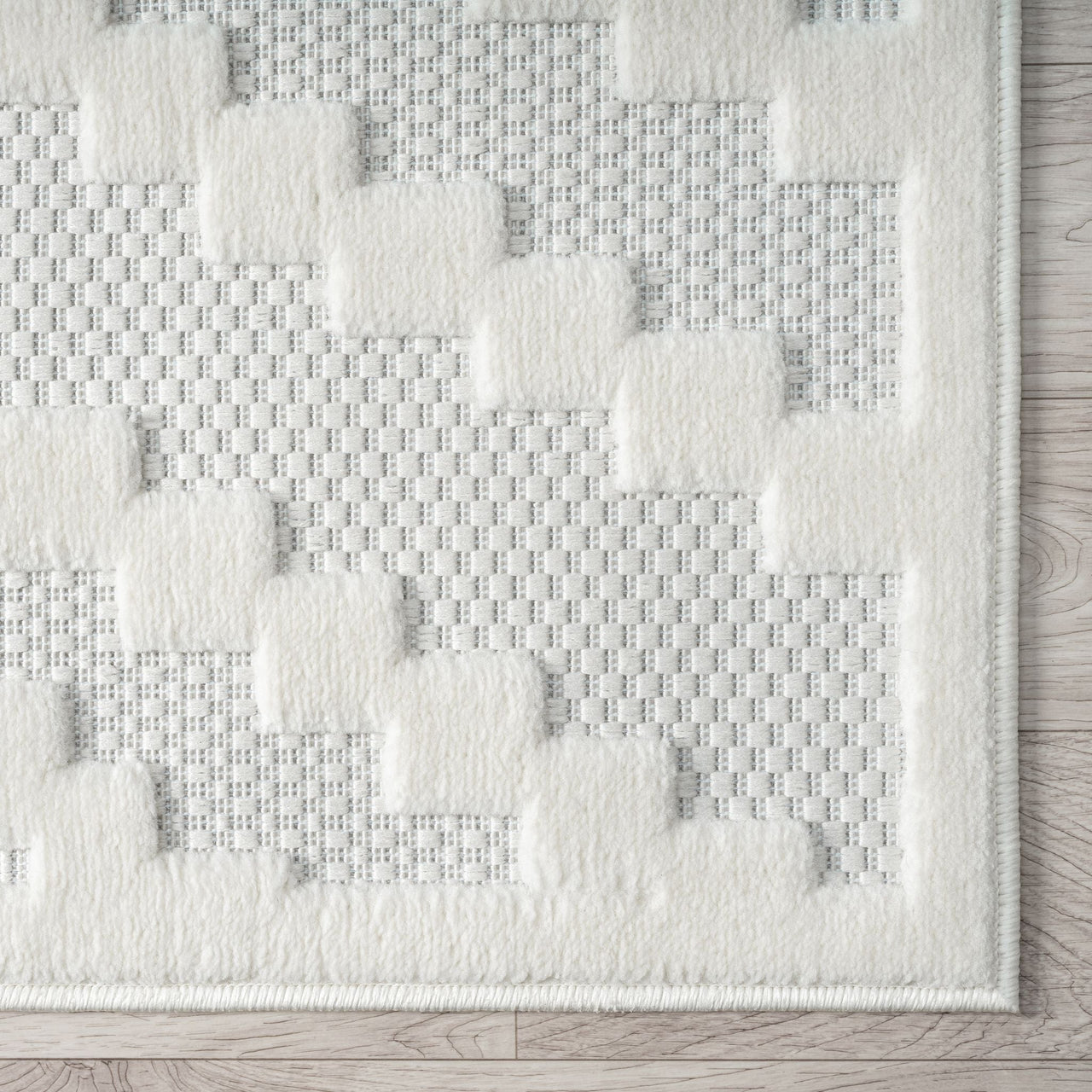Cream runner rug with textured geometric blocks on a soft woven background and a clean border edge.