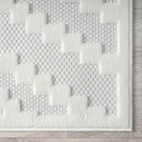 Cream runner rug with textured geometric blocks on a soft woven background and a clean border edge.