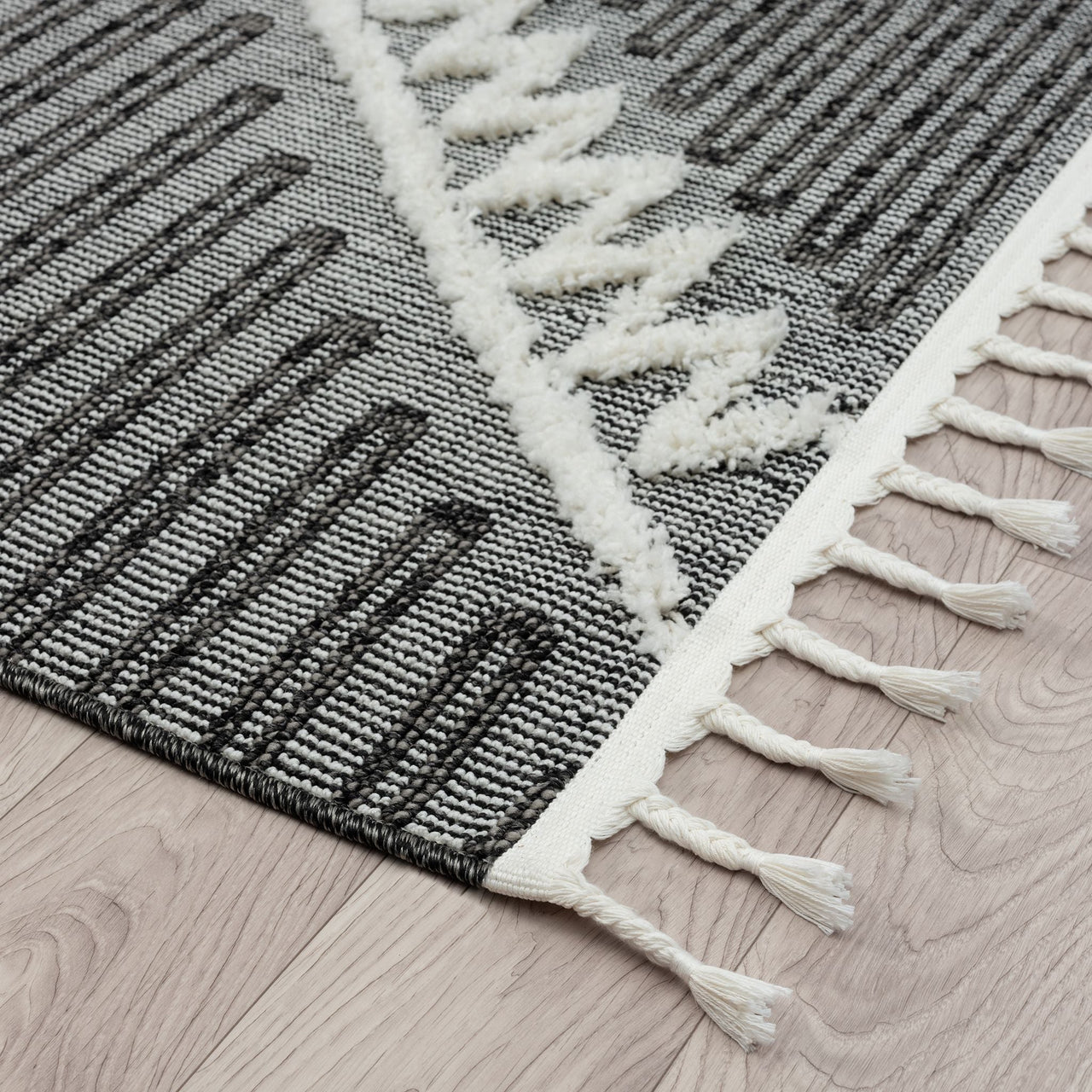 Grey and white runner rug with geometric zigzag and striped pattern, textured pile, fringed edges.