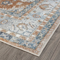 Multi-colored transitional runner rug with geometric patterns in blue, beige, and rust tones on grey wood floor.
