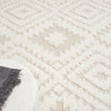 Beige and white modern geometric patterned rug with textured diamond shapes and fringed edges.