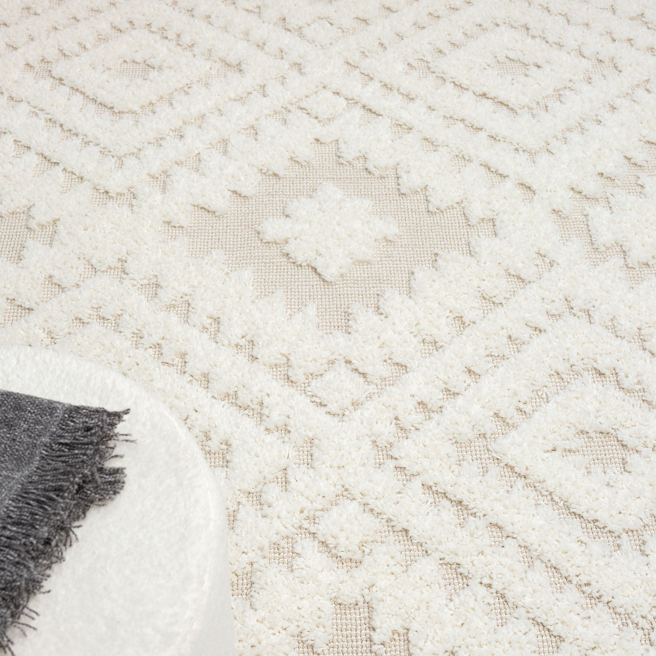 Beige and white modern geometric patterned rug with textured diamond shapes and fringed edges.