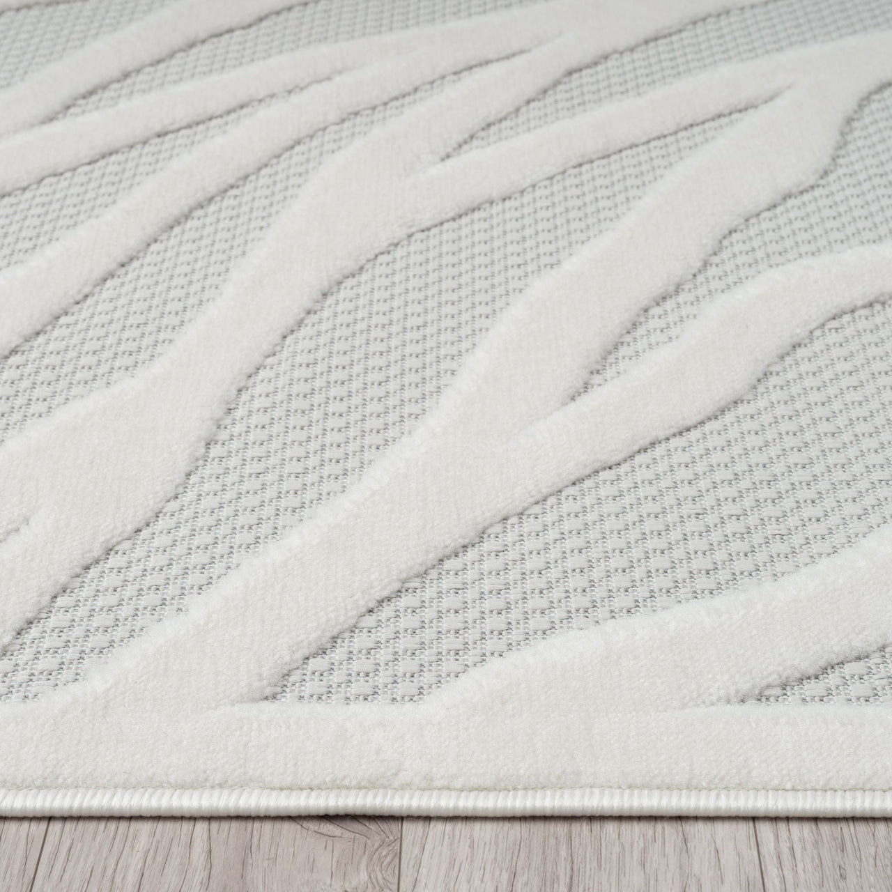 Ivory runner rug with raised geometric pattern and textured polypropylene pile.