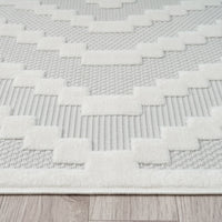 Cream runner rug with textured geometric stepped pattern on a light beige background.