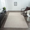 Taupe flatweave rug with subtle geometric texture on dark wood floor in modern minimalist room.
