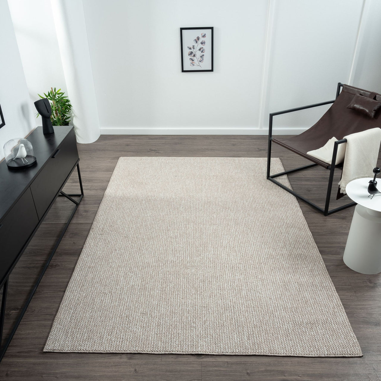 Taupe flatweave rug with subtle geometric texture on dark wood floor in modern minimalist room.