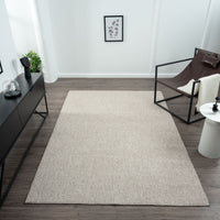 Taupe flatweave rug with subtle geometric texture on dark wood floor in modern minimalist room.