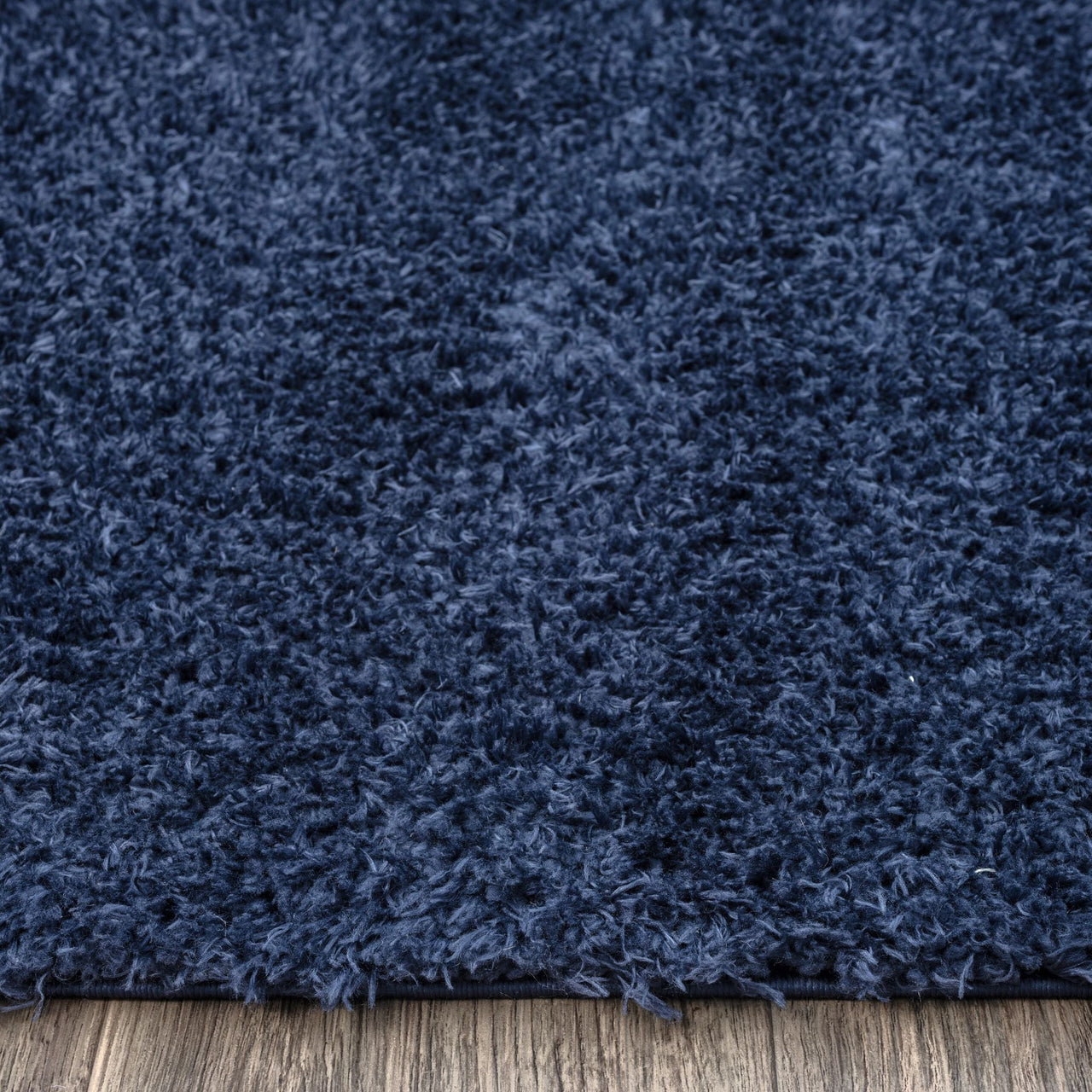 Navy blue modern shaggy runner rug with dense polyester fibers on wooden floor.