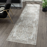 Light grey and beige modern runner rug with subtle distressed floral pattern on dark wood floor.