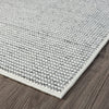 Grey flatweave runner rug with textured geometric pattern and white edge on dark wood floor.
