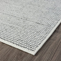 Grey flatweave runner rug with textured geometric pattern and white edge on dark wood floor.