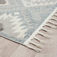 Grey and cream geometric patterned runner rug with textured pile and fringed edges on light wood floor.