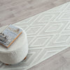 Grey and white runner rug with textured diamond geometric pattern on light neutral background.