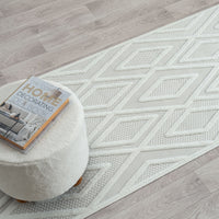 Grey and white runner rug with textured diamond geometric pattern on light neutral background.