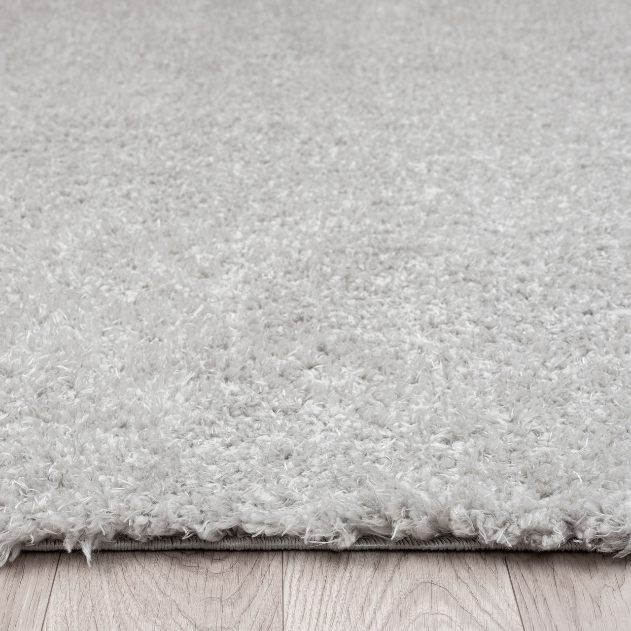 Light grey modern shaggy runner rug with dense polyester pile on wood floor.