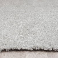 Light grey modern shaggy runner rug with dense polyester pile on wood floor.