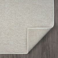 Beige flatweave runner rug with subtle geometric texture and clean stitched edges on dark wood floor.