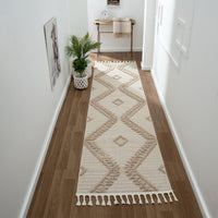 Taupe and beige geometric patterned runner rug with textured pile and fringed edges on hardwood floor.