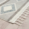 Grey and beige geometric patterned runner rug with textured pile and fringed edges on light wood floor.