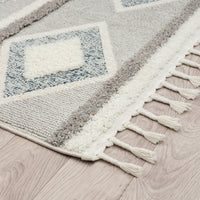 Grey and beige geometric patterned runner rug with textured pile and fringed edges on light wood floor.