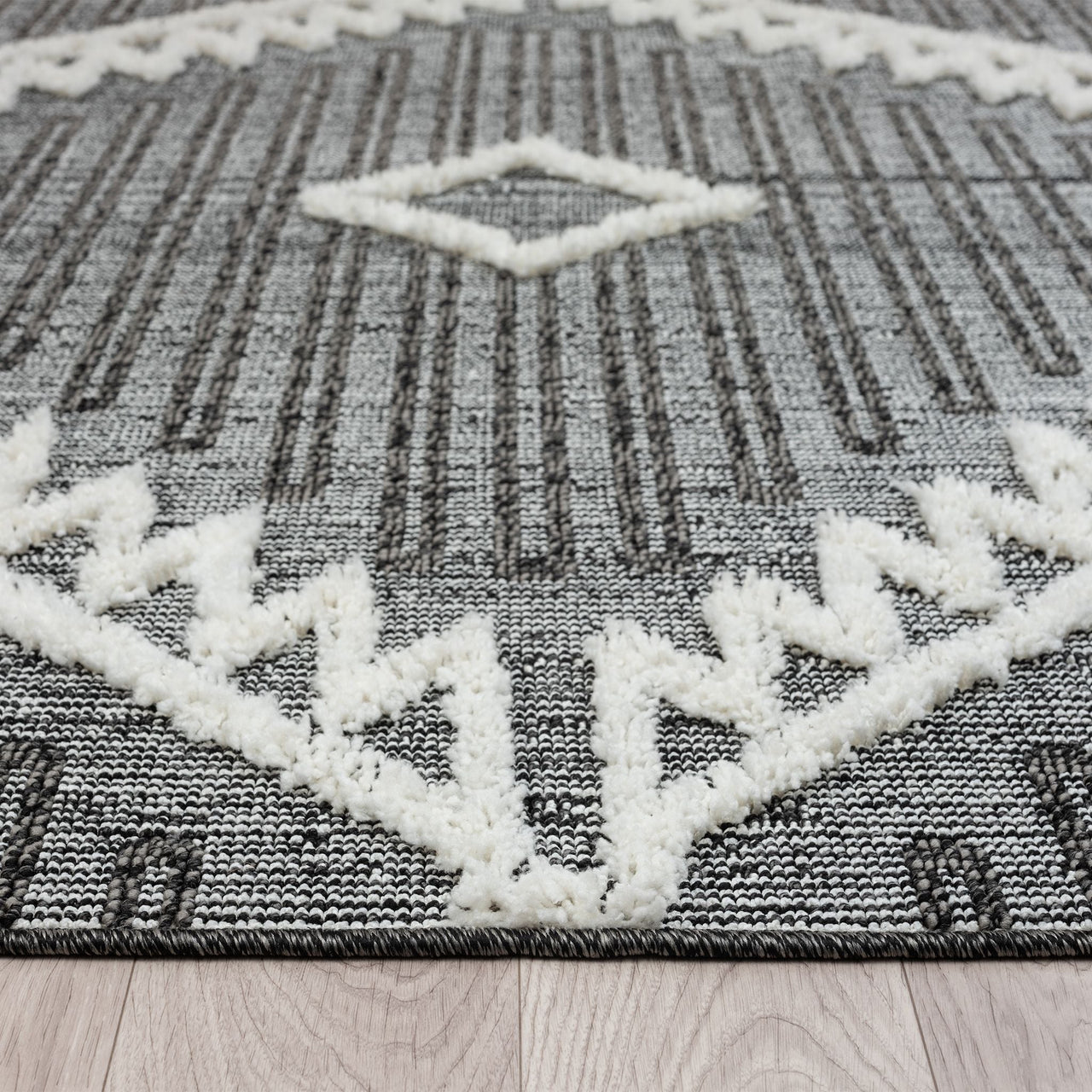 Grey and white runner rug with modern geometric pattern and textured fringed edges.