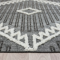 Grey and white runner rug with modern geometric pattern and textured fringed edges.