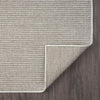 Beige flatweave runner rug with subtle geometric pattern and neatly bound edges on dark floor.