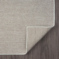 Beige flatweave runner rug with subtle geometric pattern and neatly bound edges on dark floor.