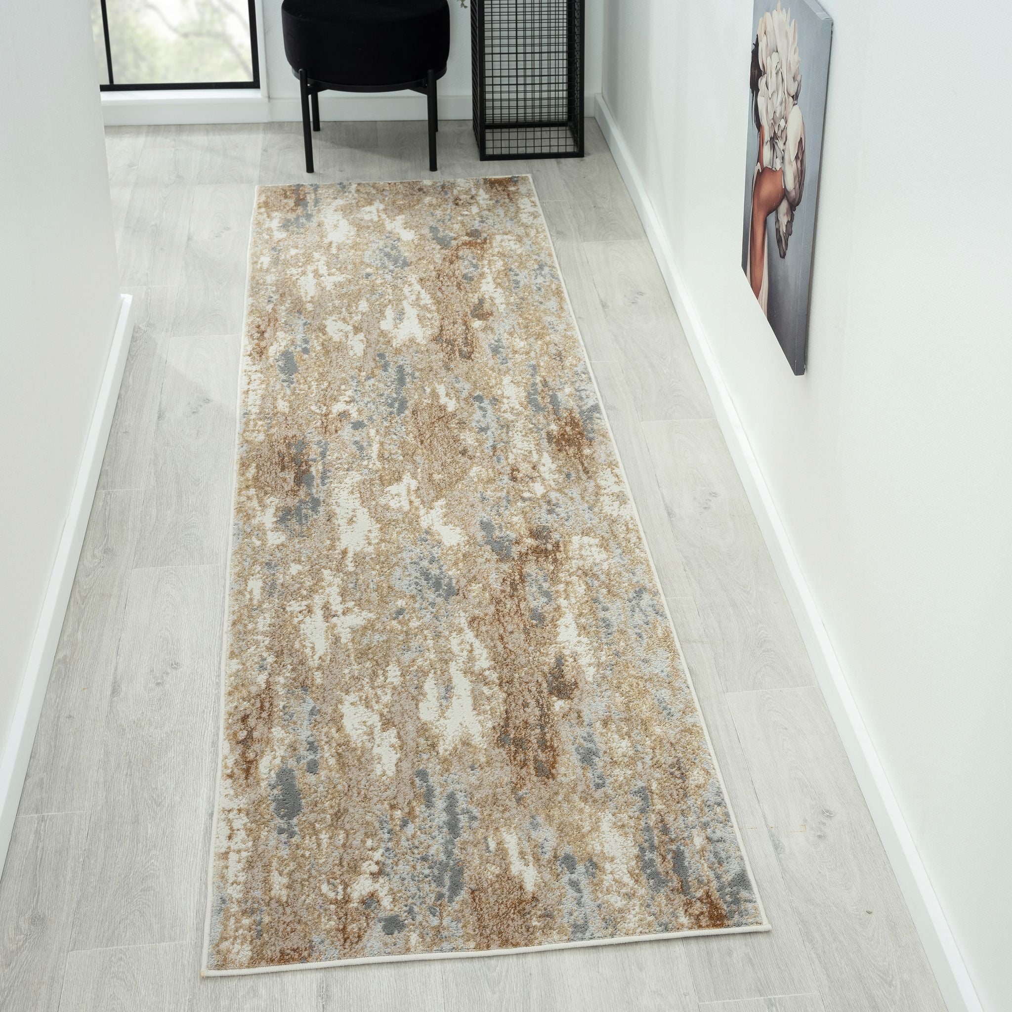 Long, patterned rug on a light wooden floor with a chair and wall art in the background.