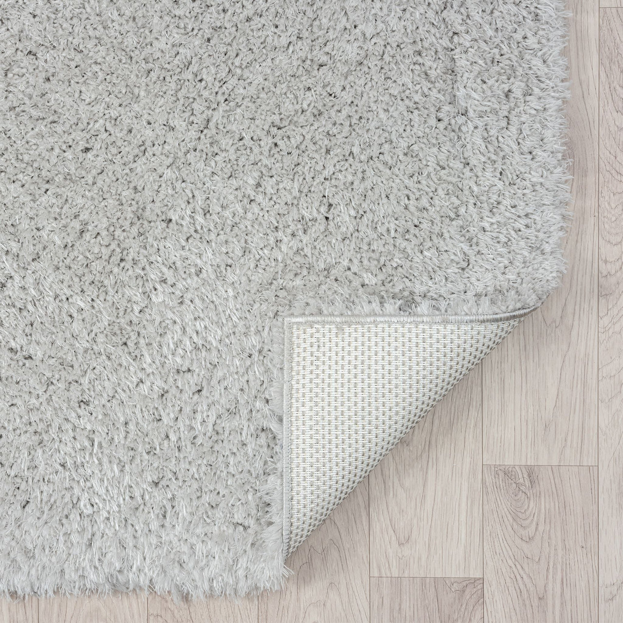 Grey modern shaggy runner rug with dense plush polyester fibers and non-slip backing on light wood floor.