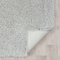 Grey modern shaggy runner rug with dense plush polyester fibers and non-slip backing on light wood floor.
