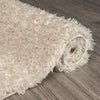 Beige modern shaggy runner rug with thick polyester fibers rolled on wood floor.