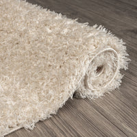 Beige modern shaggy runner rug with thick polyester fibers rolled on wood floor.