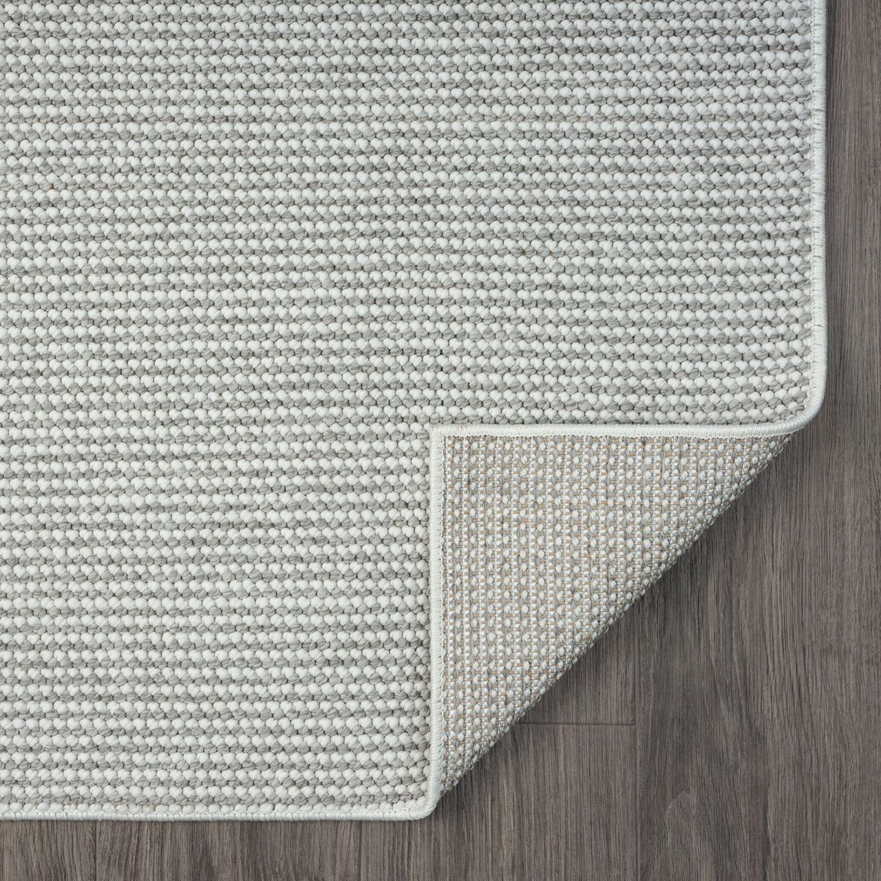 Silver grey flatweave runner rug with subtle geometric texture and neatly finished edges on dark wooden floor.