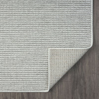 Silver grey flatweave runner rug with subtle geometric texture and neatly finished edges on dark wooden floor.