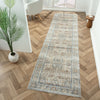 Long coral runner rug with intricate blue and beige floral patterns on wooden herringbone floor.