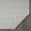 Silver grey flatweave rug with subtle geometric texture and clean, finished edges on dark wood floor.