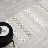 Beige and cream runner rug with textured geometric zigzag and wavy patterns and fringed edges on light floor.