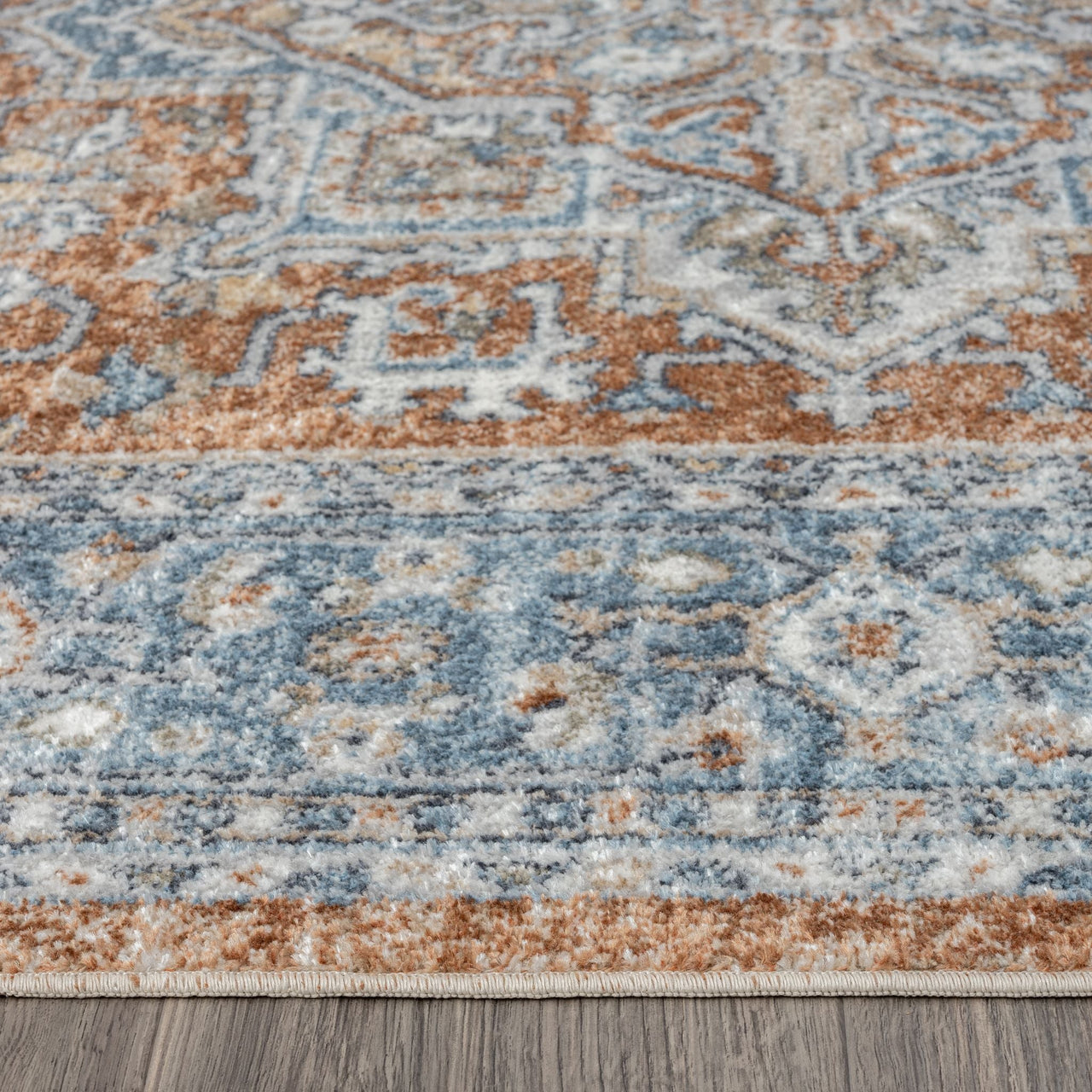 Blue, rust, and cream transitional rug with intricate geometric and floral patterns, low pile.