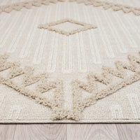 Taupe and beige rug corner with raised geometric pattern and textured fringe edges on light wood floor.