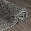 Rolled grey and silver modern shaggy runner rug with thick plush texture on dark wood floor.