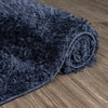Rolled navy blue shaggy runner rug with thick polyester fibers on wooden floor.