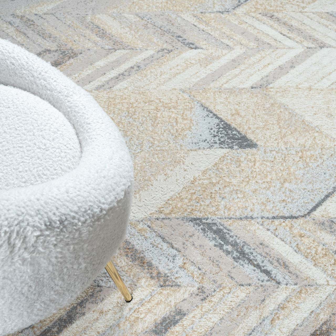 Close-up of a textured rug with a geometric pattern and a white chair corner.