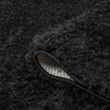 Black modern shaggy rug with thick polyester fibers and a non-slip backing edge visible.