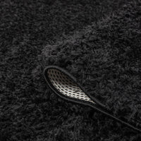 Black modern shaggy rug with thick polyester fibers and a non-slip backing edge visible.