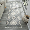 Grey and cream runner rug with modern geometric diamond pattern and fringed edges.