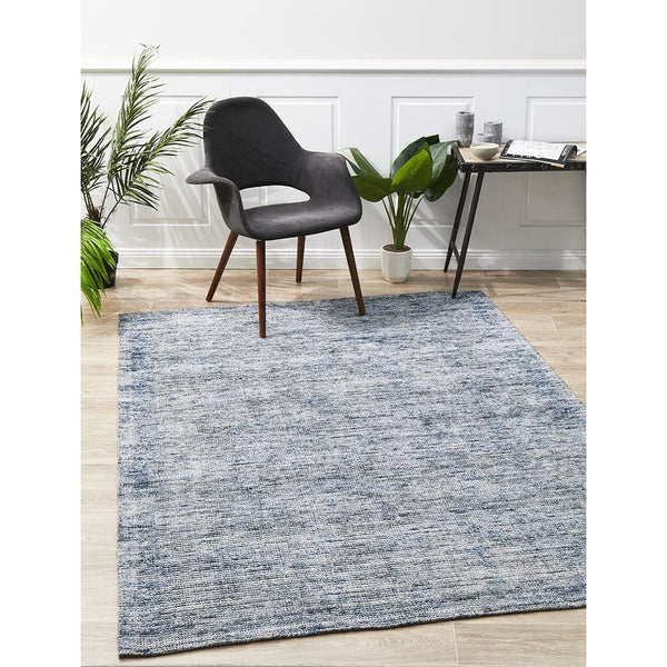 Indigo blue modern cut loop pile rayon cotton rug with subtle texture on light wood floor.