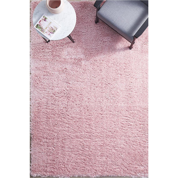 Rectangular pink shaggy rug with soft polyester pile under modern gray chair and round white side table.